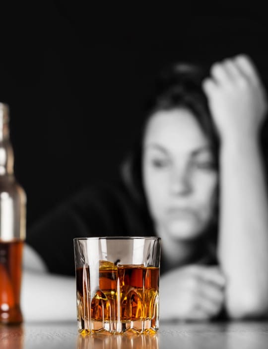 Женщина сидит за столом с алкоголем