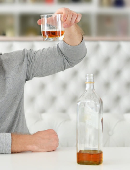 Мужчина держит стакан с алкоголем